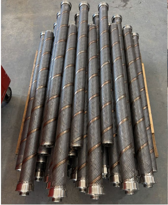 Finished stainless perforated risers stacked on the shop floor.